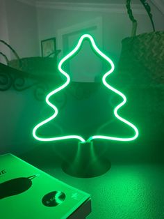 a green neon christmas tree sitting on top of a table next to a laptop computer