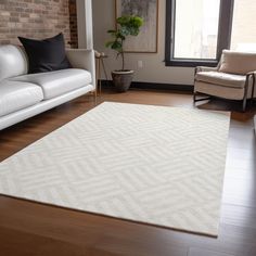 a living room with two white couches and a large rug on the hardwood floor