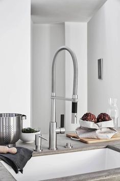 a kitchen sink that has some food on the counter and in front of it is a bowl of fruit