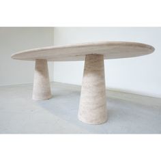 a table made out of concrete sitting on top of a white floor next to a wall