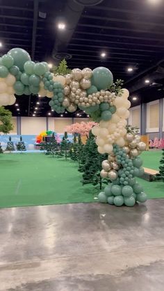 an arch made out of balloons in the middle of a room filled with trees and other decorations