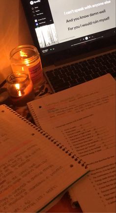 a laptop computer sitting on top of a desk next to a cup filled with candles