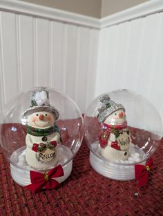 two snowmen are sitting inside glass domes