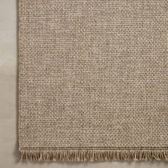 a beige rug with fringes on the bottom and one side is folded in two different directions