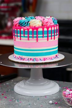 a cake with pink, blue and white frosting sitting on top of a table