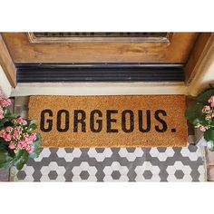 a door mat with the word gorgeous on it next to some flowers and potted plants