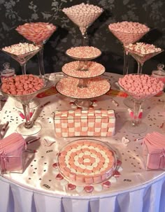 a table topped with lots of pink and white desserts covered in candies on top of plates