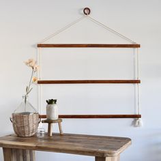 a wooden table topped with a vase filled with flowers next to a wall mounted shelf