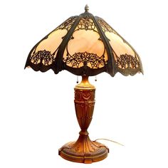 a lamp that is sitting on top of a wooden stand with a glass shade over it