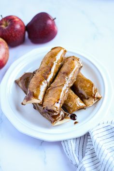 some food is on a white plate next to apples