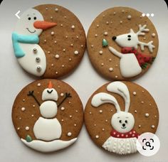 four decorated cookies with frosting on top of each cookie, one has a snowman and the other is a polar bear