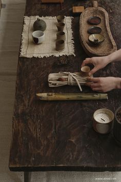 two people are making wooden spoons on a table with bowls and other items around them