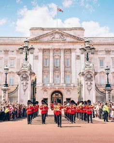 the guards are marching in front of buckingham palace, where people are gathered to watch