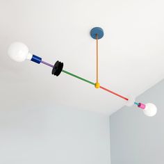 three different colored lights hanging from the ceiling in a room with white walls and flooring