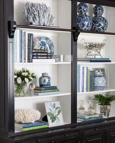 a black bookcase filled with books and vases