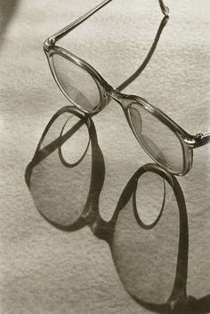 a pair of glasses sitting on top of a piece of paper with the reflection of them