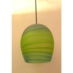 a green lamp hanging from a ceiling in a room with a white wall behind it