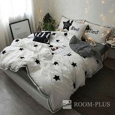 a white bed with black and white stars on the comforter next to a potted plant