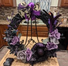 a wreath with purple flowers on top of a wooden table next to a cell phone