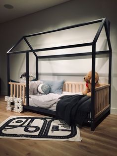 a child's bed with a canopy over it and a teddy bear on the floor