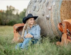 a woman wearing a cowboy hat sitting in the grass