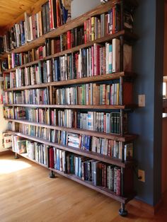 a bookshelf filled with lots of books on top of a hard wood floor