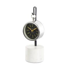 a small white clock sitting on top of a stand