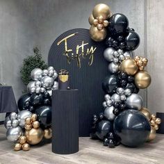 an arch made out of black and gold balloons