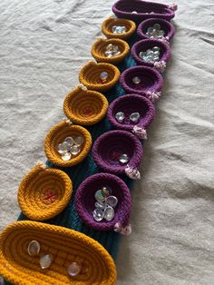 a row of crocheted baskets sitting on top of a white table covered in buttons