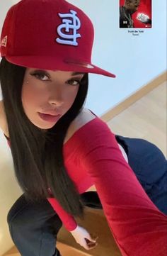 a woman with long hair wearing a red baseball cap and blue jeans, posing for the camera