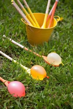 an assortment of colored pencils in a yellow bucket on the grass next to eggs