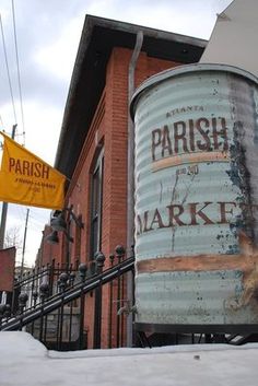 an old barrel sitting on the side of a building next to a fence and snow