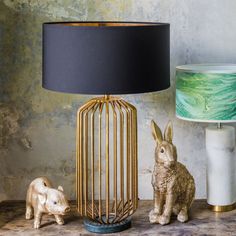 two small animals sitting next to a lamp on a table