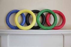 four different colored rings sitting on top of a fireplace mantel in front of a wall