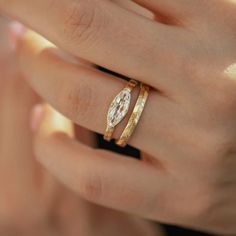 a woman's hand holding a gold ring with a diamond in the middle and two diamonds on each band