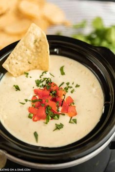 a black crock pot filled with white quesadilla dip and tortilla chips