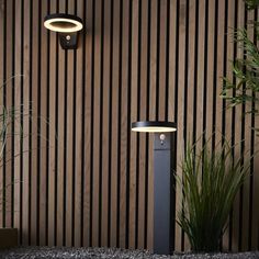 a modern outdoor light in front of a wooden wall