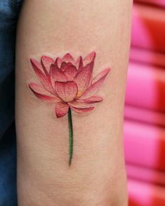 a pink flower tattoo on the arm