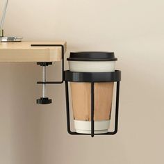 a coffee cup hanging from the side of a wall next to a desk with a lamp on it