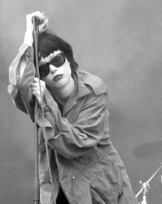 a man with sunglasses on holding onto a pole while standing in front of a stage