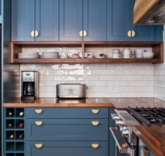 a kitchen with blue cabinets and wooden counter tops, including a coffee pot on the stove