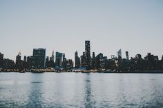 the city skyline is lit up at night from across the water, with skyscrapers in the distance