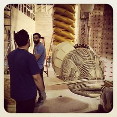 two men standing next to each other in front of a sculpture