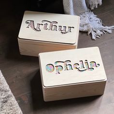 two wooden boxes sitting on top of a wood floor next to a rug and vase