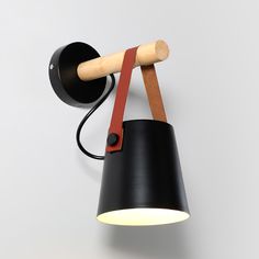 a black wall light with a wooden arm and red strap around it's neck