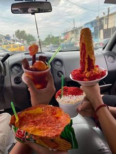 three people sitting in the back seat of a car holding plates with food on them