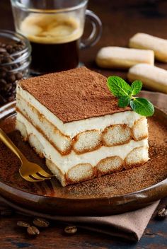 a piece of tirami cake on a plate with coffee and bananas in the background