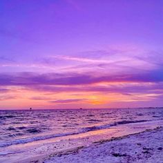 the sun is setting over the ocean with purple and pink clouds in the sky above it