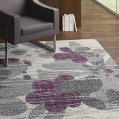 a chair sitting on top of a wooden floor next to a purple and white rug