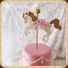 there is a pink cake with white and gold decorations on the top that has a horse decoration on it